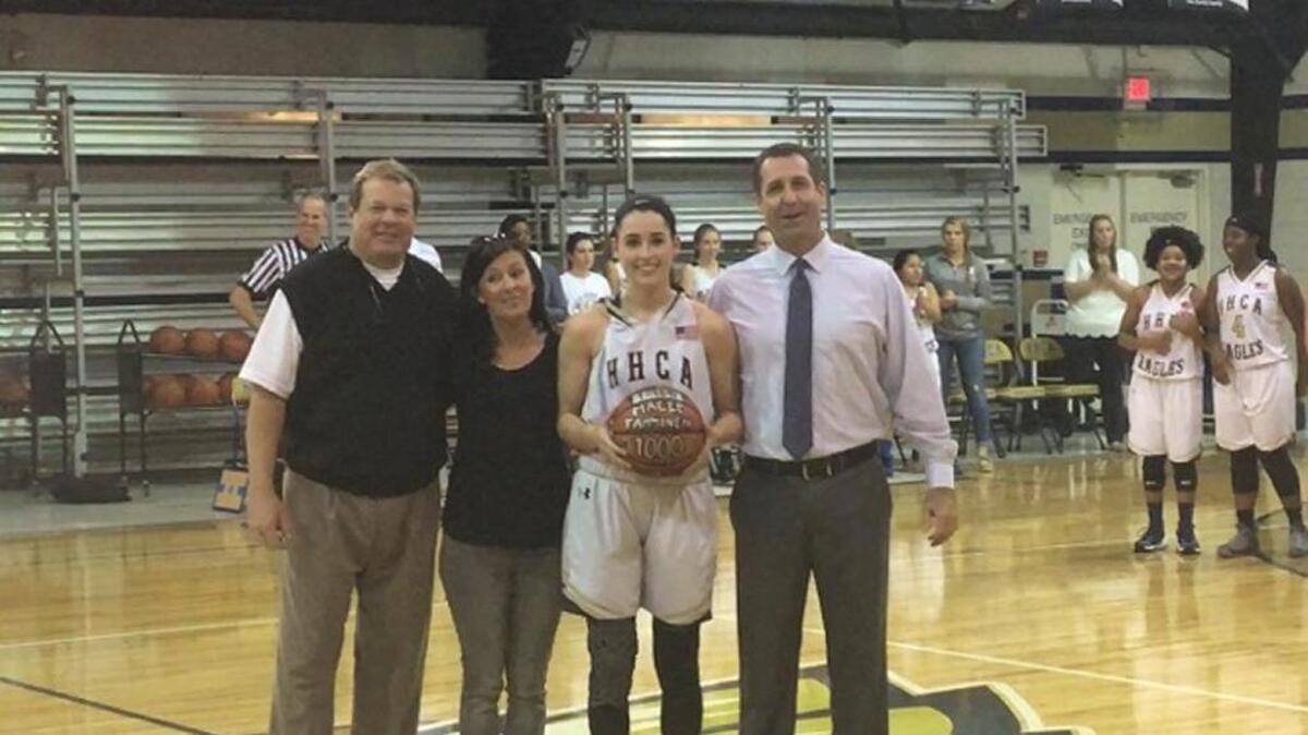 Hilton Head Christian’s Macee Tamminen shows off the ball used to score her 1,000th career point Friday night, joined by coach Kenny Conroy (left) and parents Heather and Mac Tamminen.