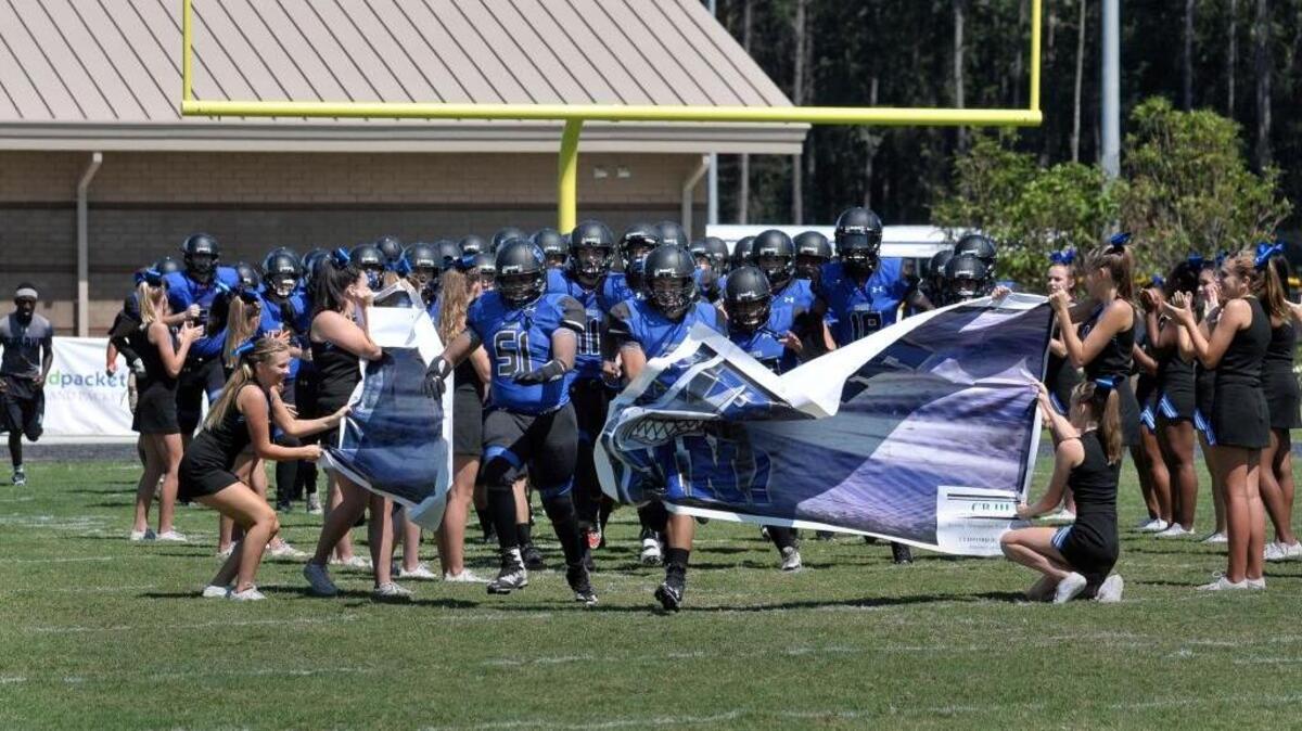 The May River Sharks crash through a banner held by the first-year team’s cheerleaders Saturday afternoon at their on-campus stadium. The first home contest in school history, originally slated for Friday night, was postponed a day because of Tropical Storm Hermine. The Sharks lost to Whale Branch 41-7.