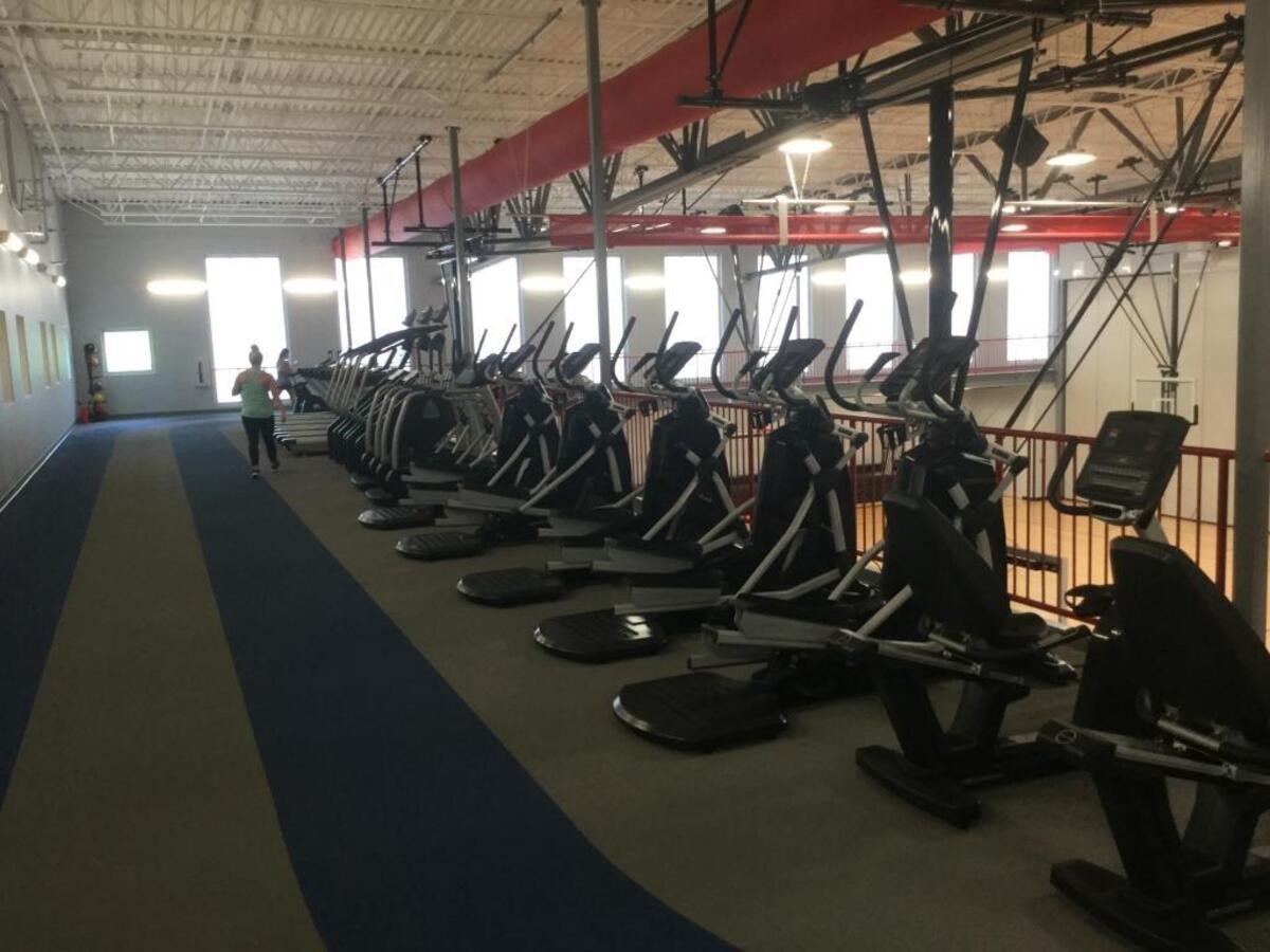 The expanded facility includes an elevated track with treadmills and cardio machines.